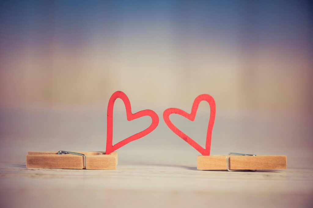 pexels-photo-776633-776633 Two wooden clothespins with red heart shapes, symbolizing love and romance, on a blurred background.