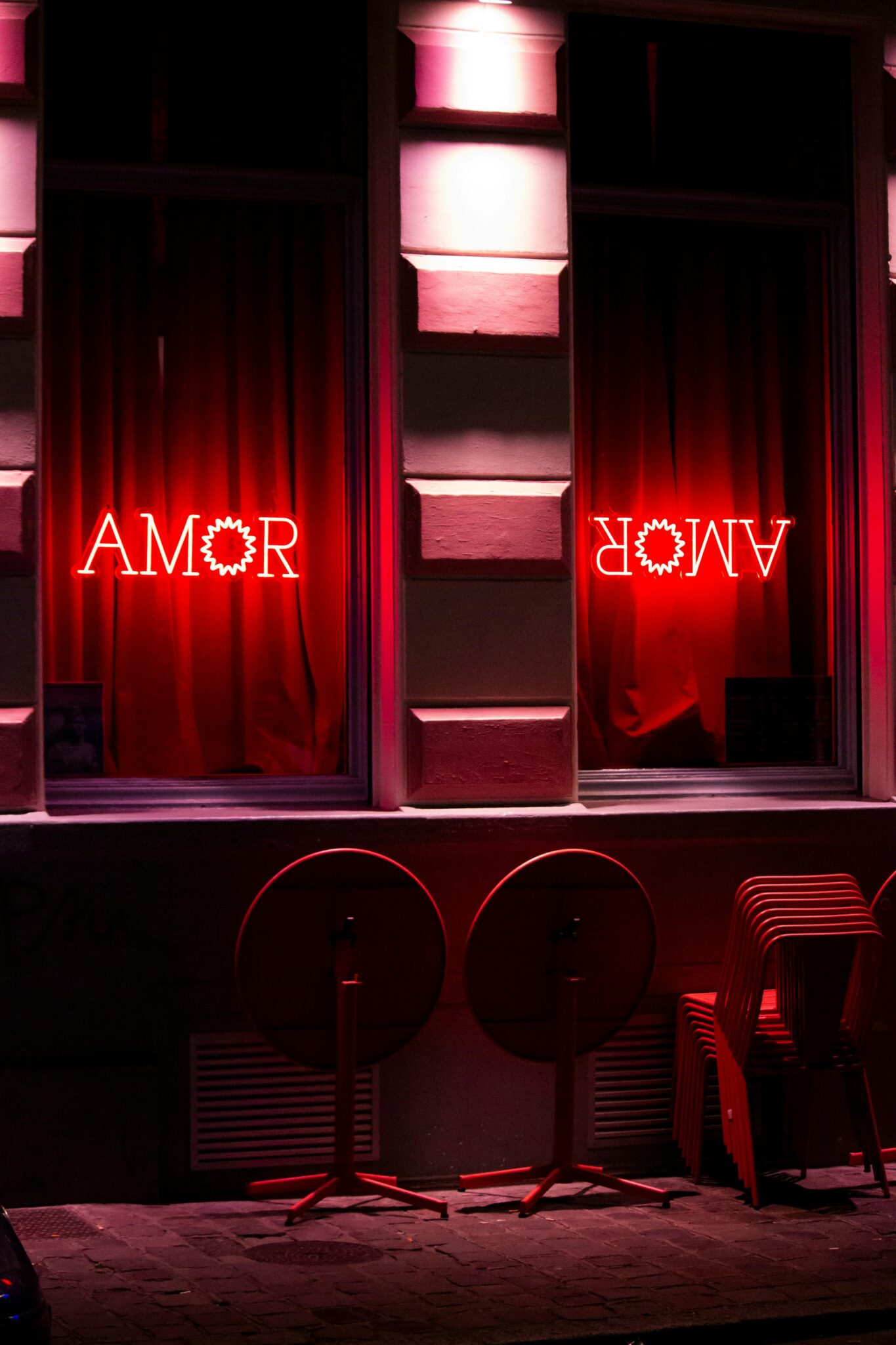 Red neon light with 'Amor' text on a Lille street at night, creating a vibrant mood.