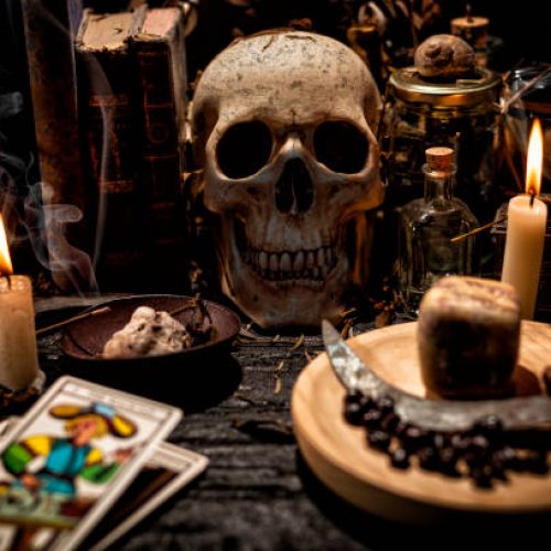 Mystical objects, Tarot cards, skull, candles, old books, knives and materials for magic rituals.